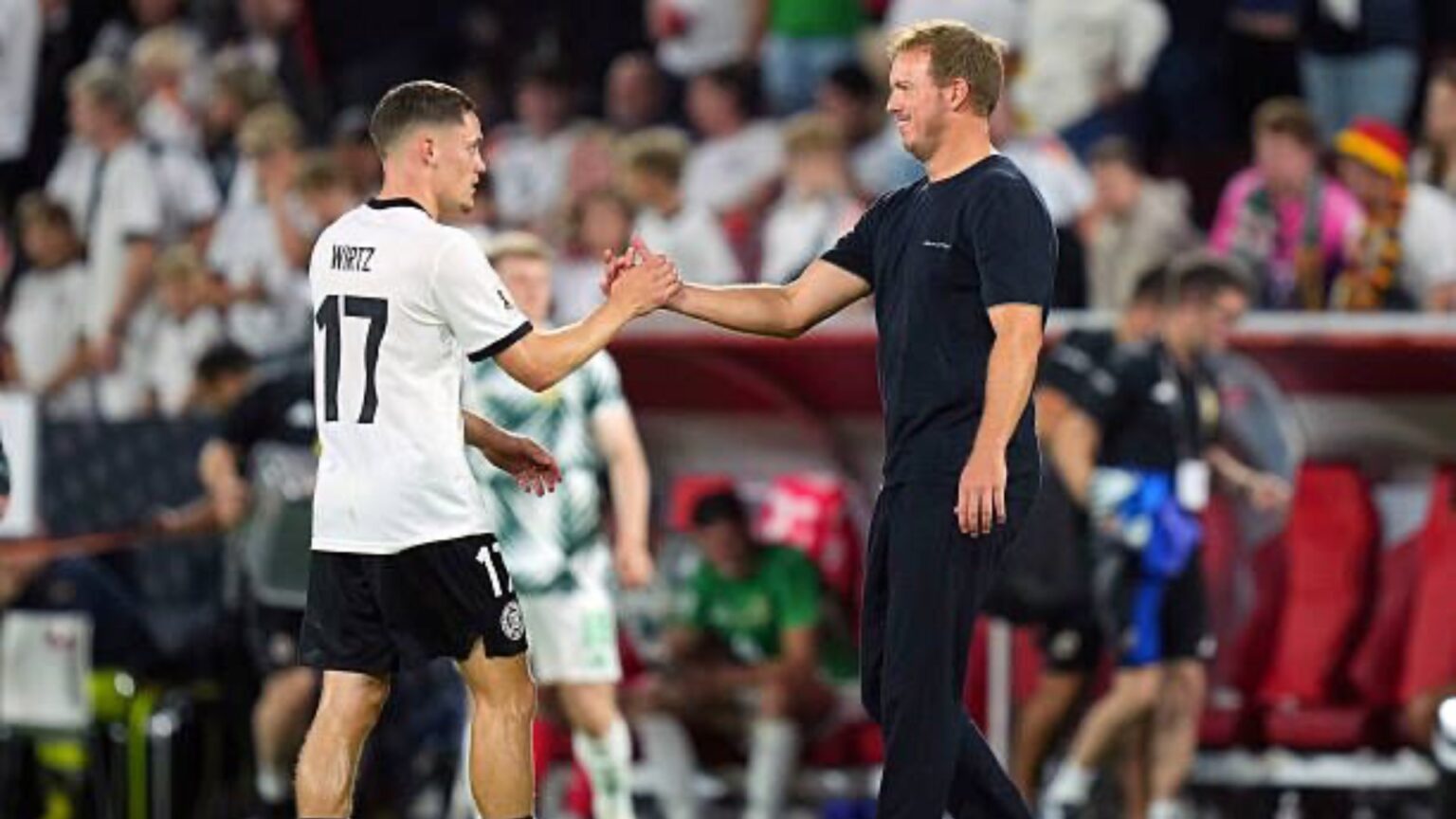 Florian Wirtz shaking hands with Julian Nagelsmann while wearing a Germany national team kit.