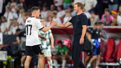 Florian Wirtz shaking hands with Julian Nagelsmann while wearing a Germany national team kit.