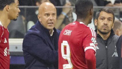 Alexander Isak in a Liverpool shirt talking to coach Arne Slot during a match.